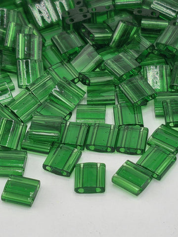 numerous green glass beads scattered across a white background.