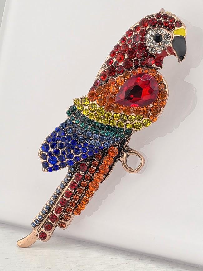 A colorful, sparkling parrot brooch made of various gemstones and materials.