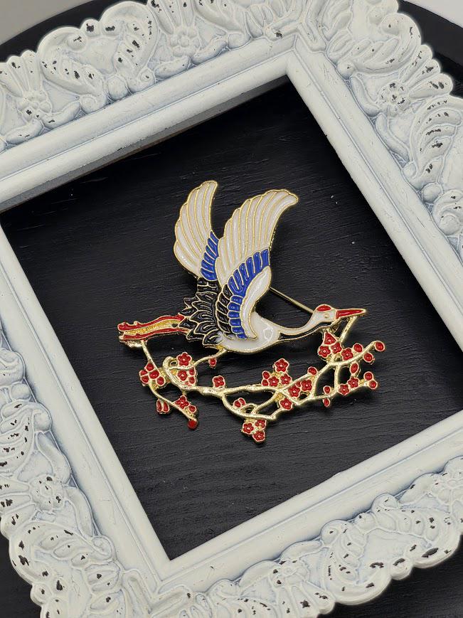 A decorative white frame with a black background, containing a framed image of a bird with blue and white feathers and red flowers.