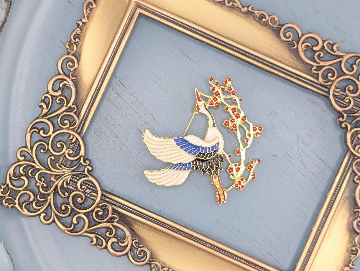 a decorative gold frame with a white bird and red flowers on a blue background.
