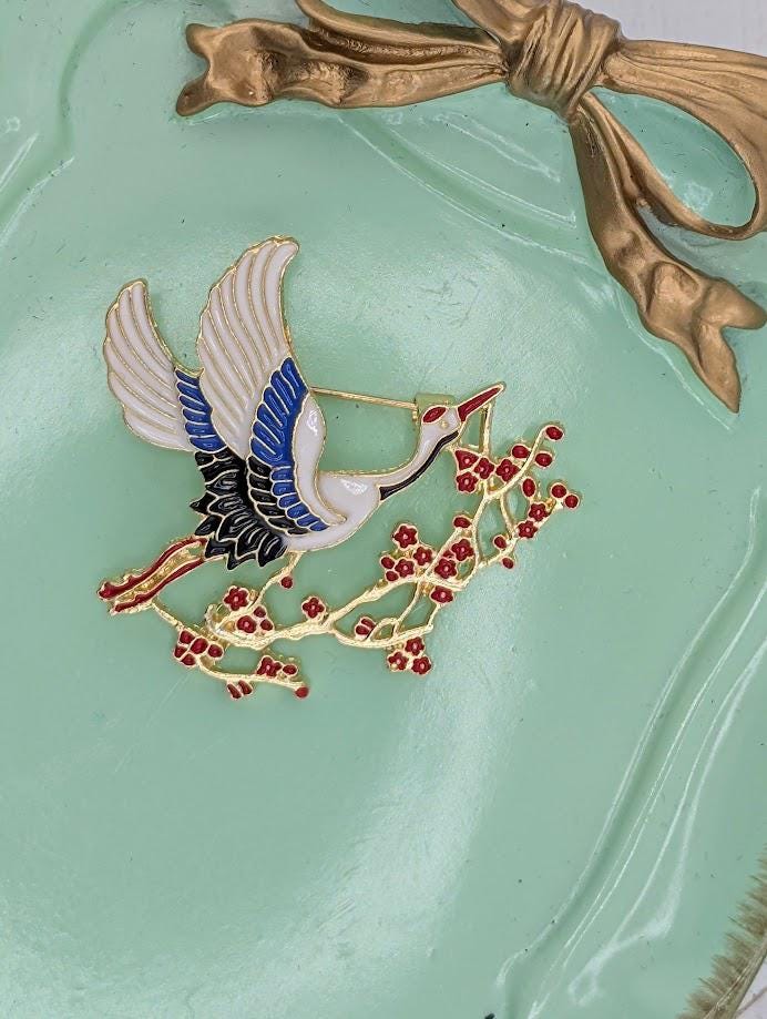 A decorative metal object with a bird-like design, featuring a combination of blue, white, and red colors, and a gold bow.