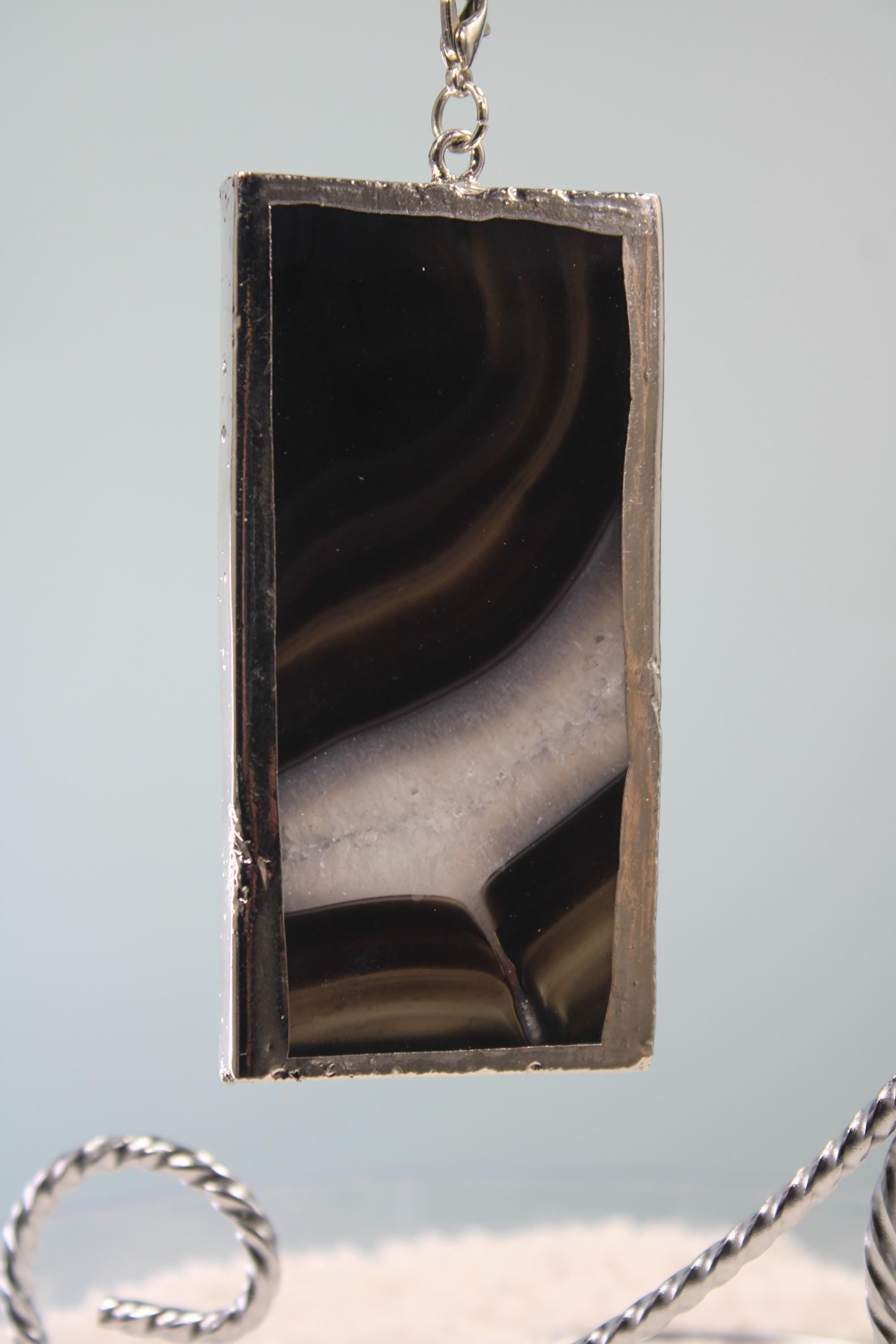 A rectangular, black and white stone with a unique, striped pattern is displayed in the image.