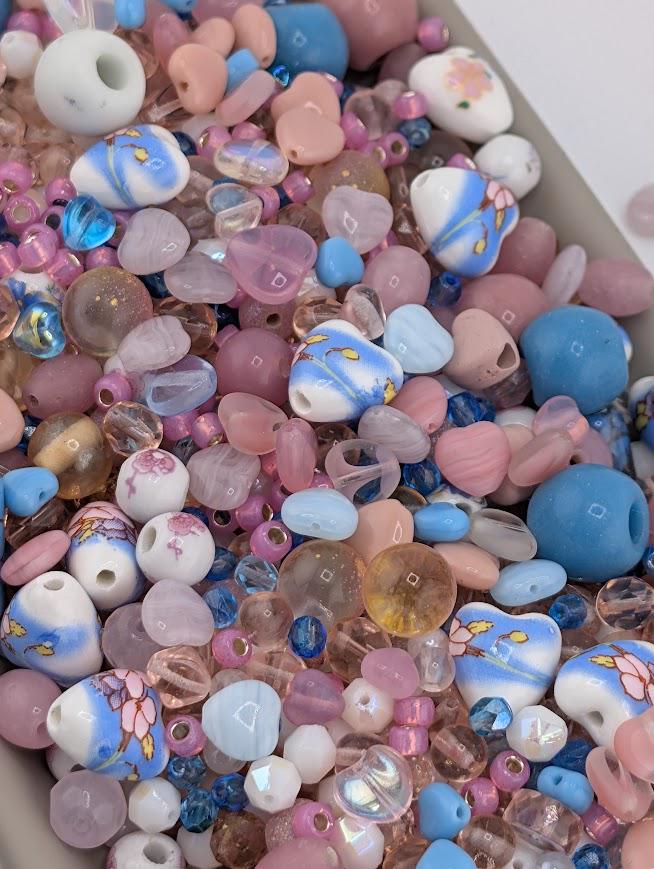 A colorful assortment of glass beads in various shades of pink, blue, and white, scattered across a surface.