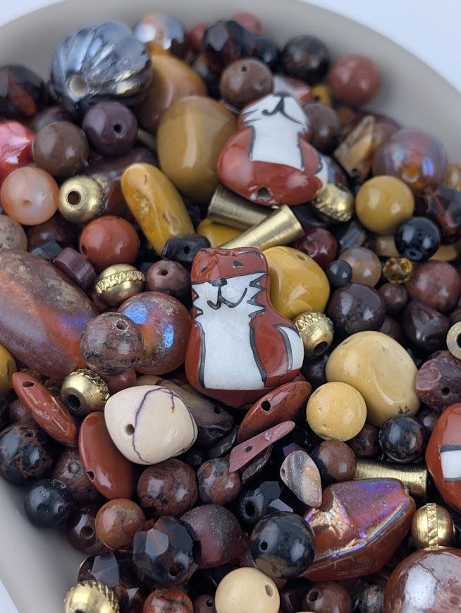 The image is a close-up of a variety of colorful beads and beads, including glass beads and beads in different shapes and sizes, arranged in a pile or a bowl.