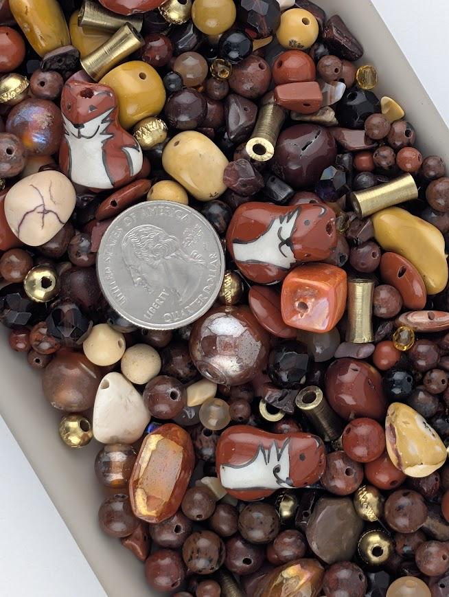 The image is a collection of various beads, coins, and other small objects, including a silver coin, arranged in a pile.
