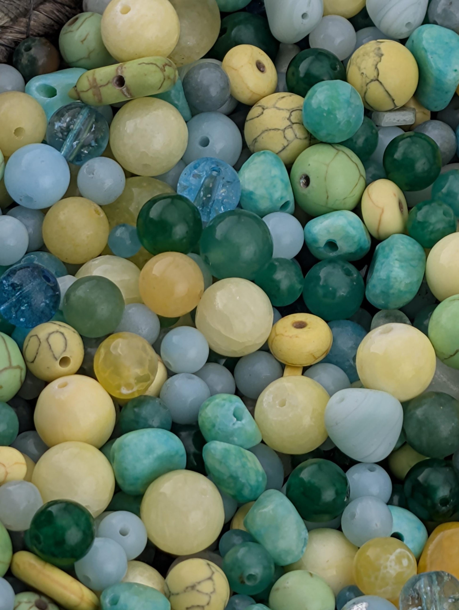 The image is a close-up of a pile of various colored beads, including turquoise, yellow, and green beads, scattered together.