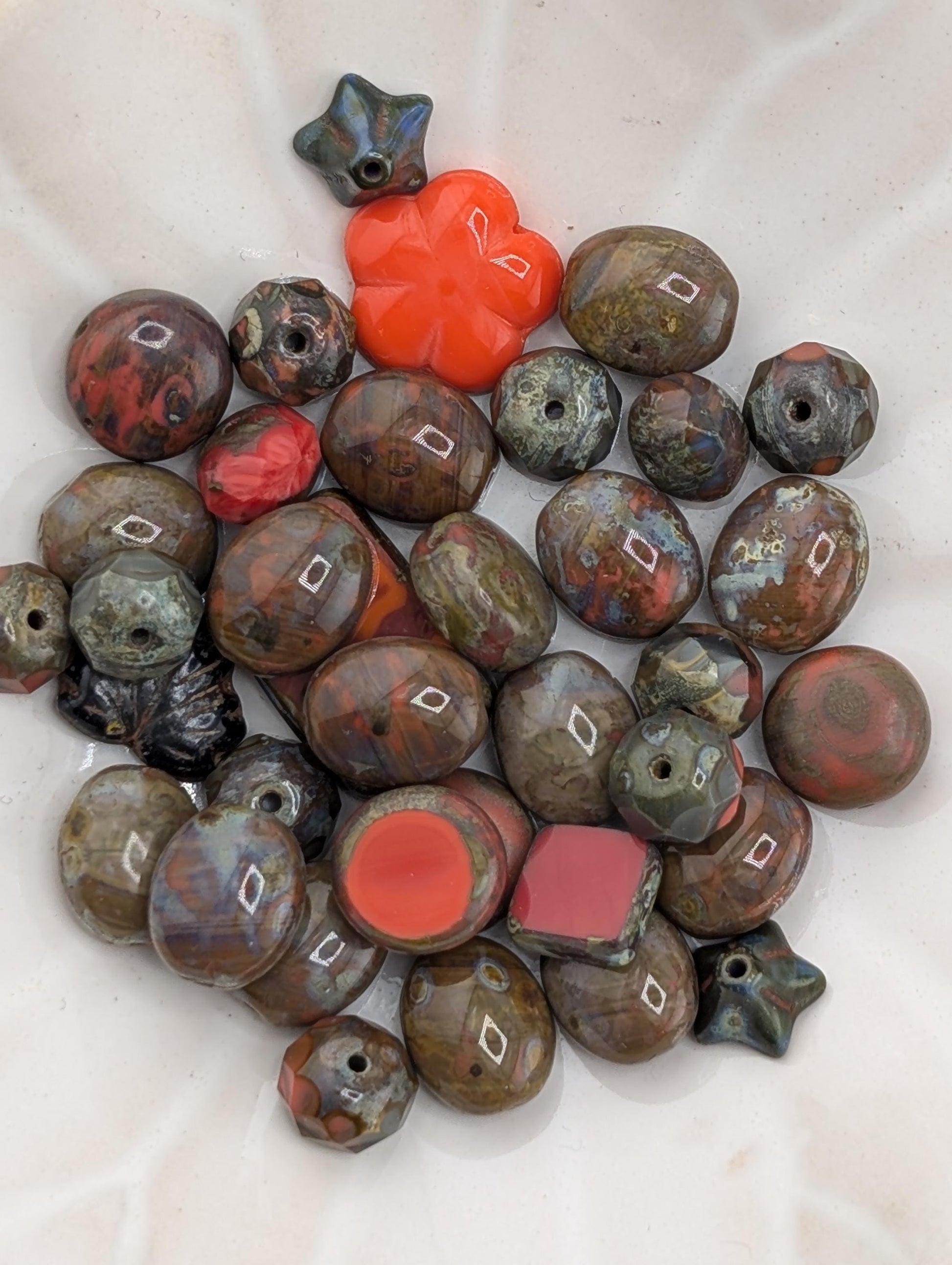 a collection of various colored beads, including red, black, and brown, arranged on a white surface.