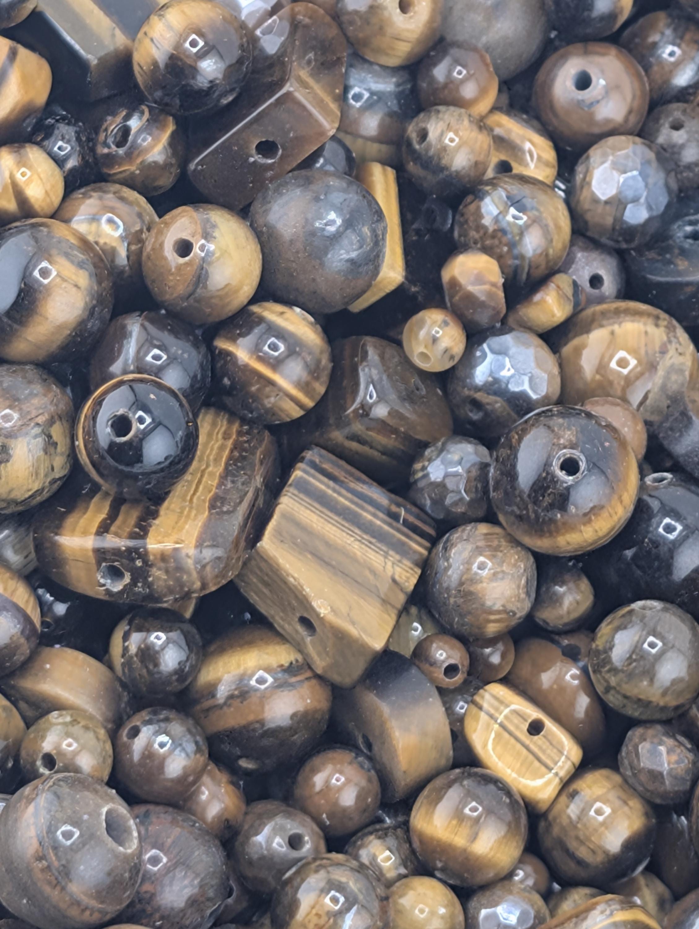 The image is a close-up of various beads and stones, including some that appear to be made of wood or other natural materials. The colors and textures of the beads and stones are diverse, creating a visually interesting and textured composition.
