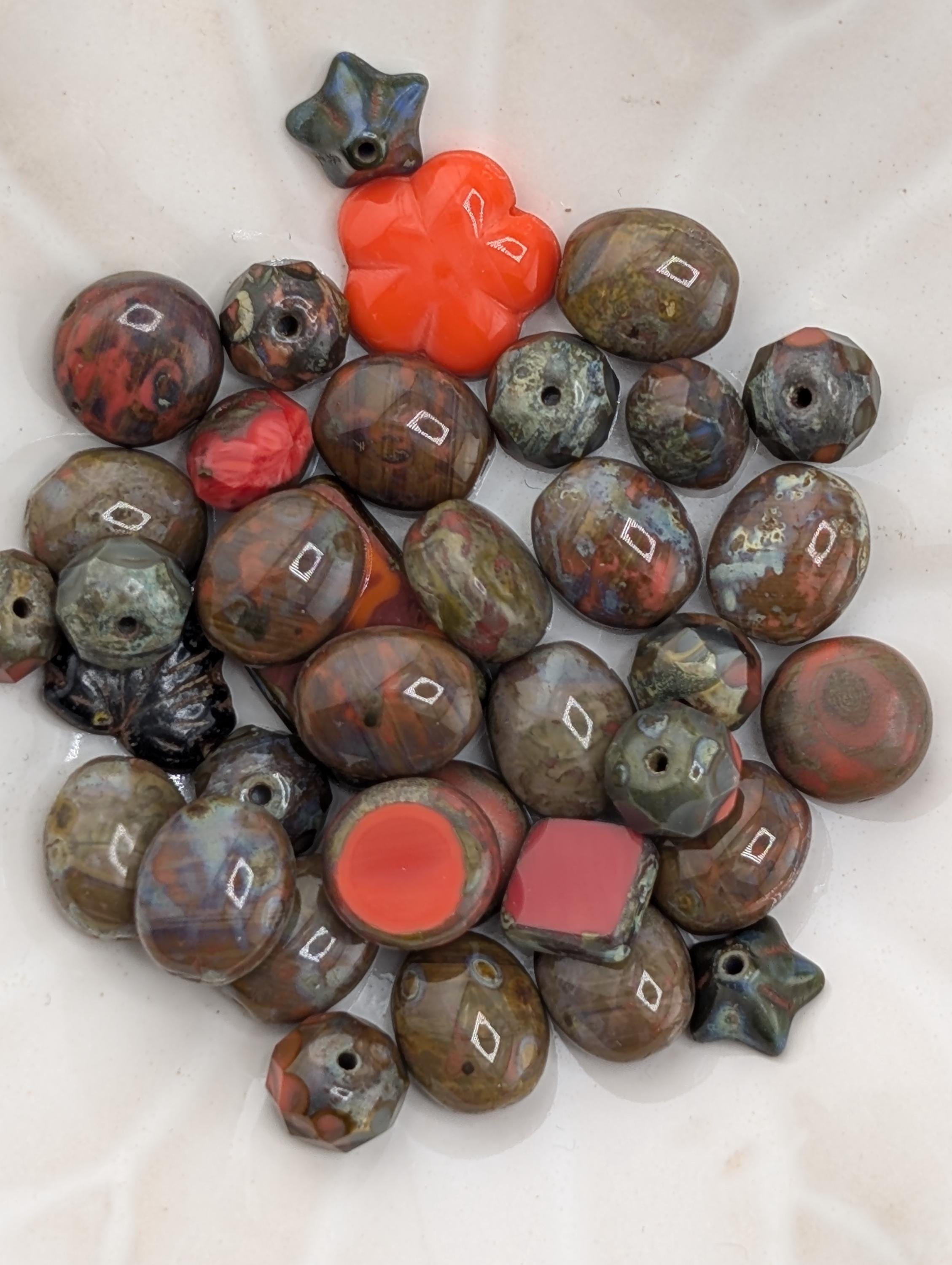 a collection of various colored beads, including red, black, and brown, arranged on a white surface.