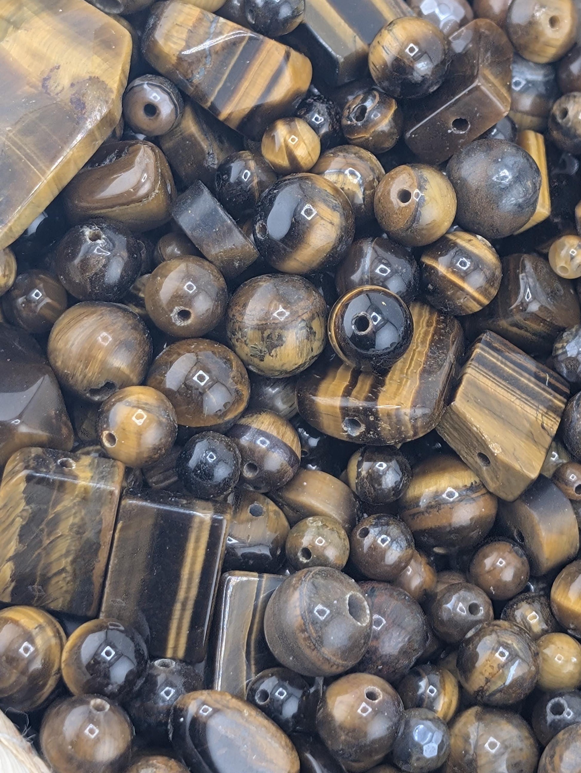 a collection of various beads and stones, including black and brown stones, arranged in a visually appealing manner.