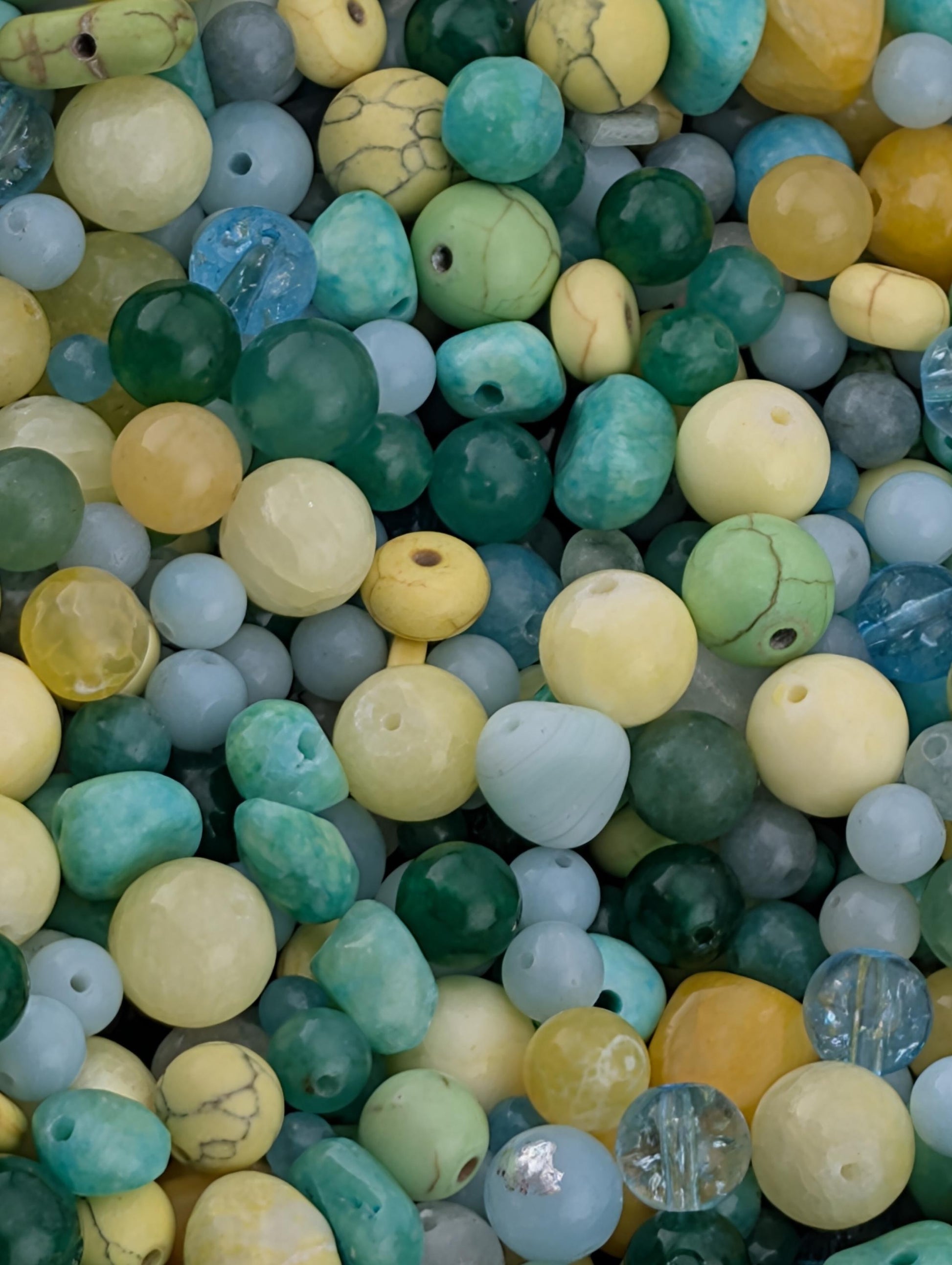 The image is a close-up of a collection of various colored beads, including turquoise, yellow, and blue beads, scattered together.