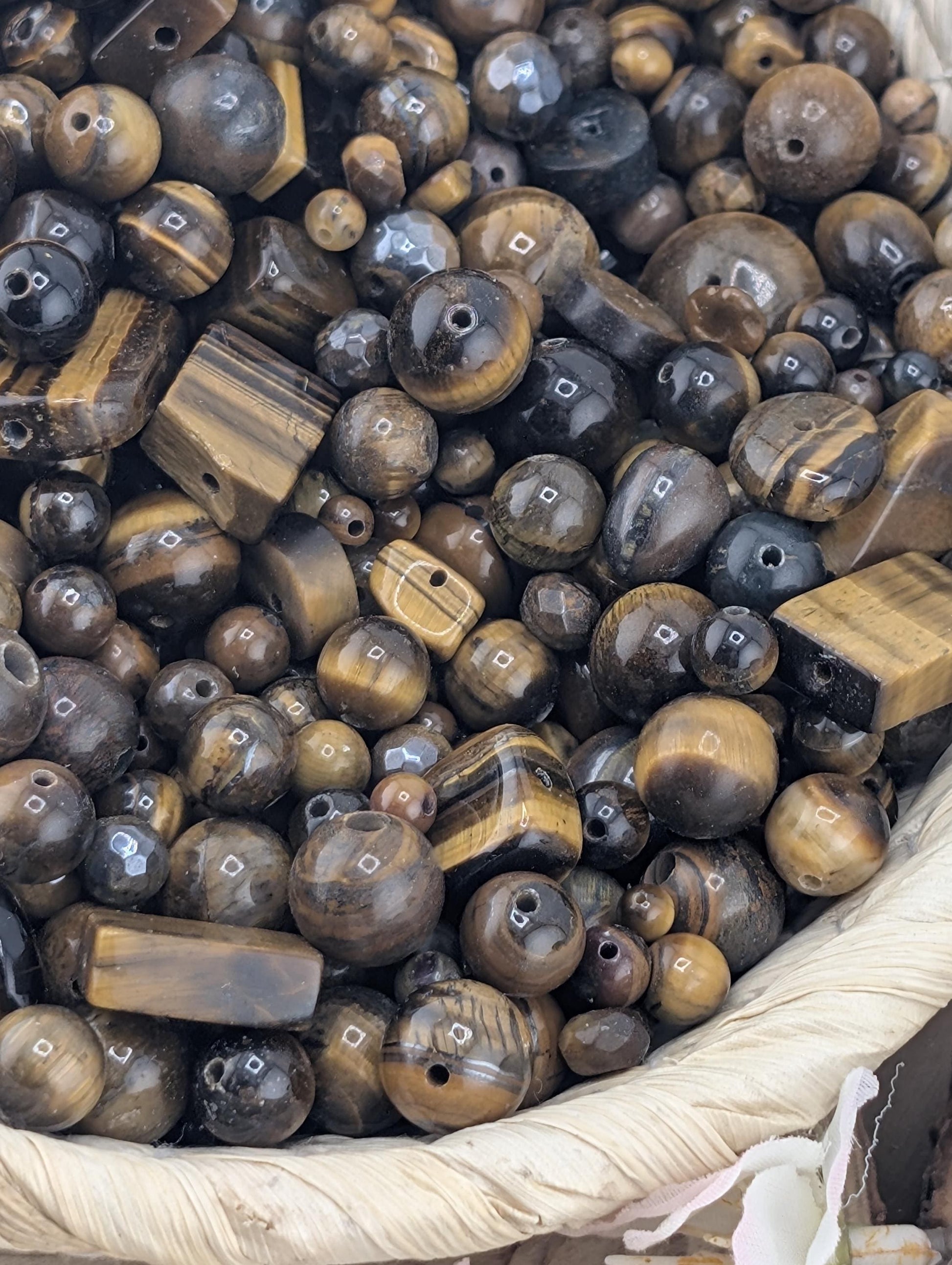 a close-up view of a collection of various beads and beads, including black, brown, and gold-colored beads, arranged in a basket or container.