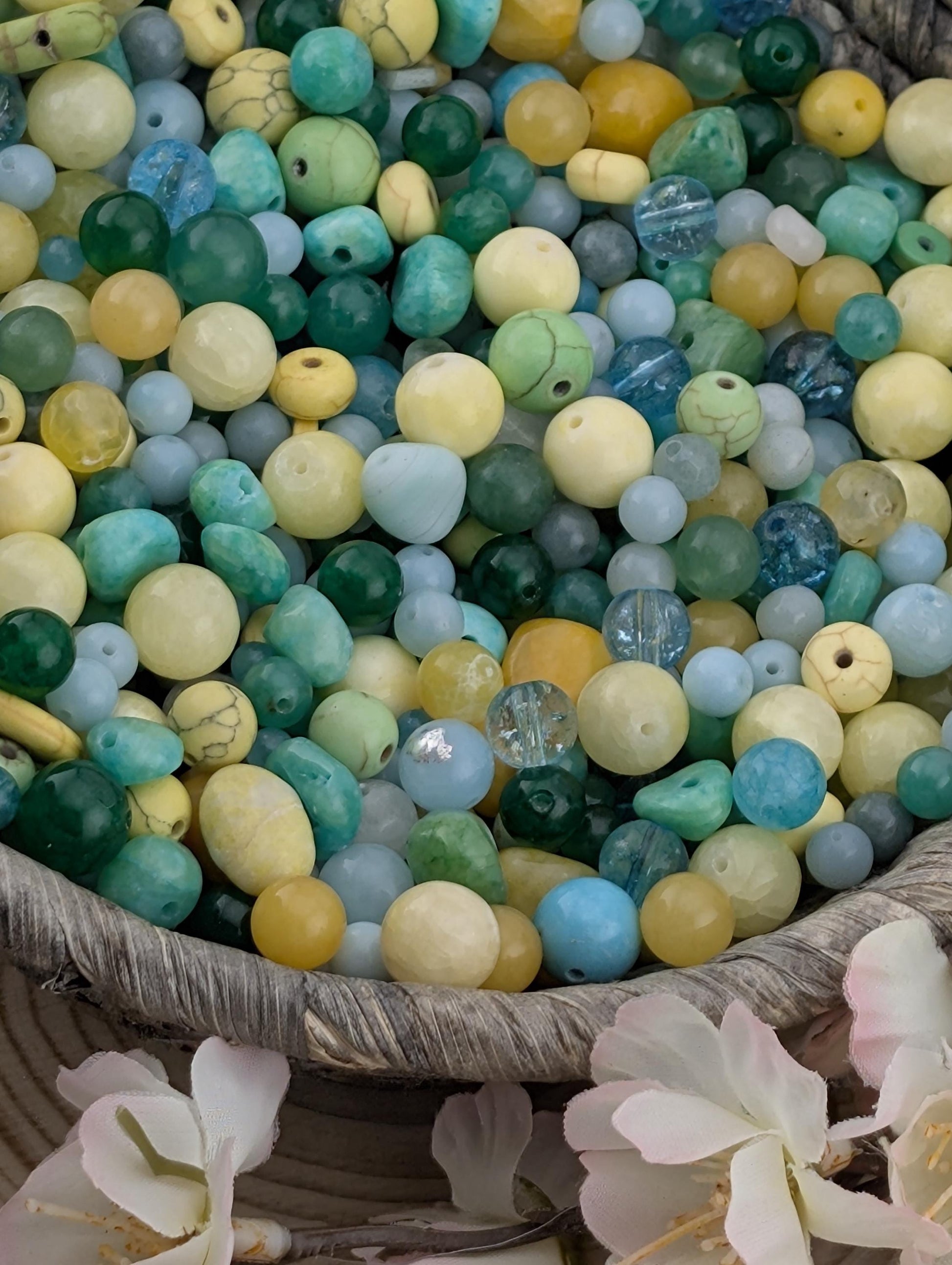 a large collection of colorful beads and stones, including various shades of blue, green, yellow, and white, arranged in a basket or container.