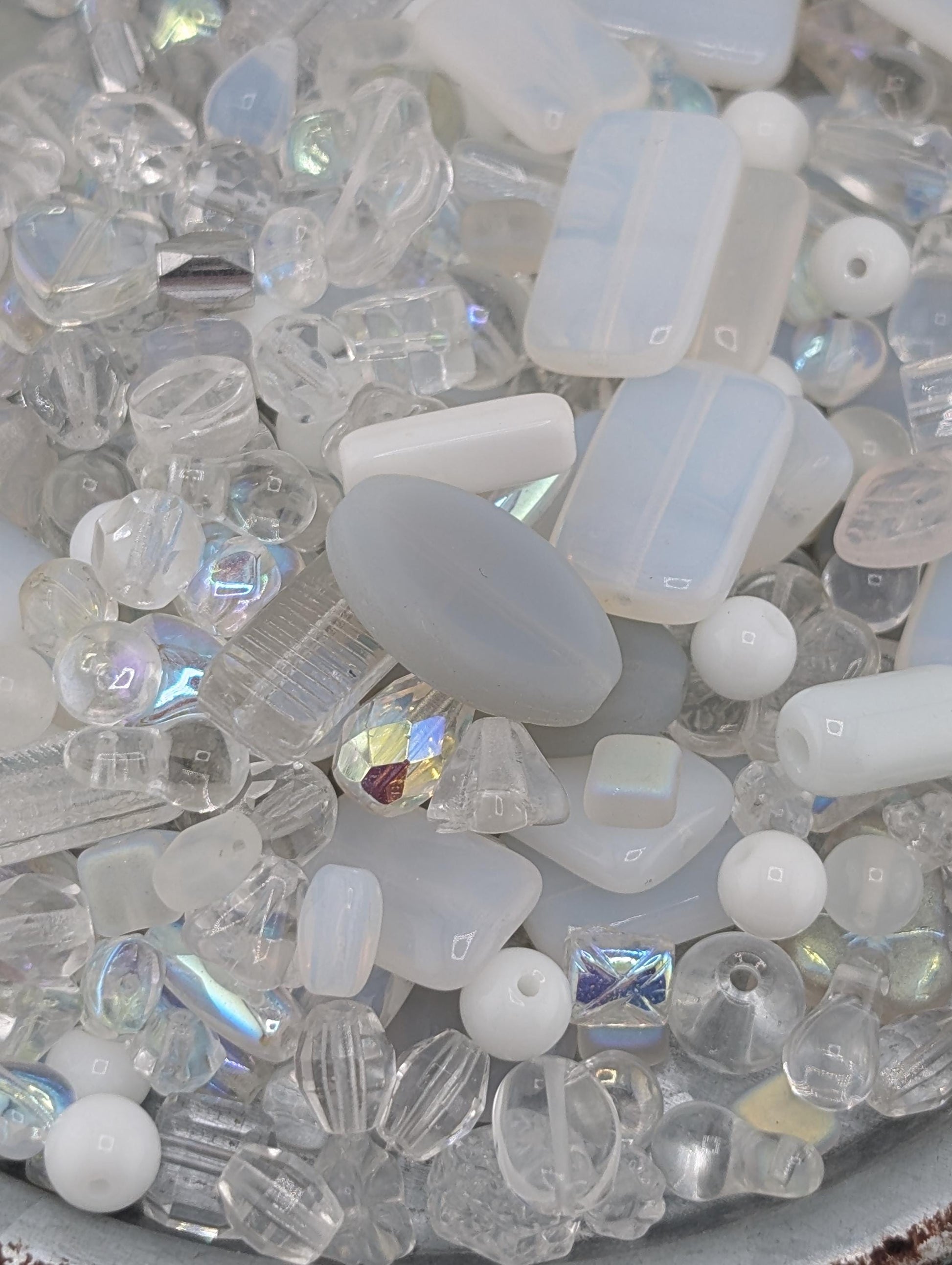 a variety of clear glass beads and crystals, including round, square, and rectangular shapes, scattered together in a visually appealing manner.