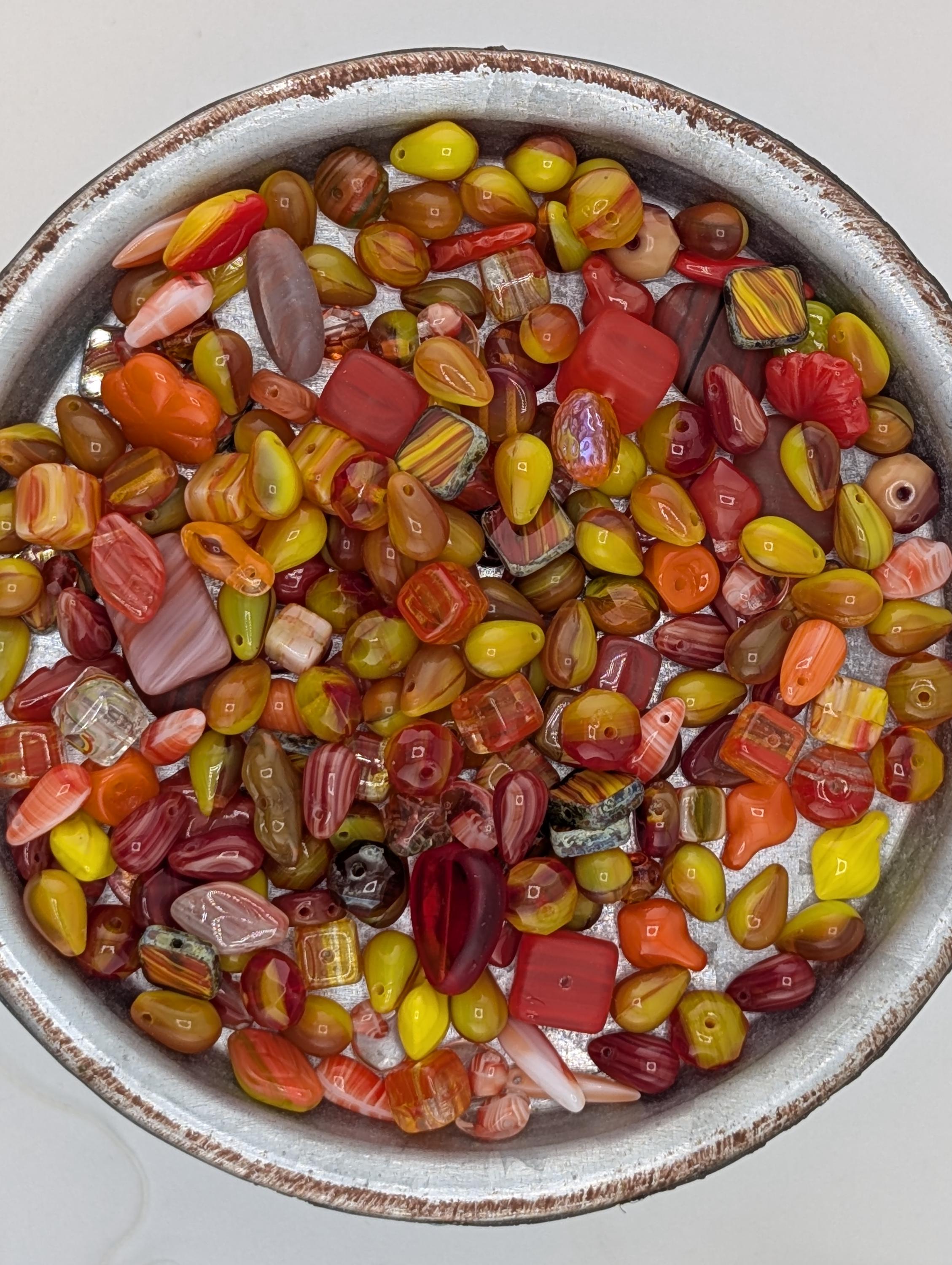 A bowl filled with a variety of colorful beads, including red, orange, yellow, and green beads, creating a vibrant and visually appealing display.