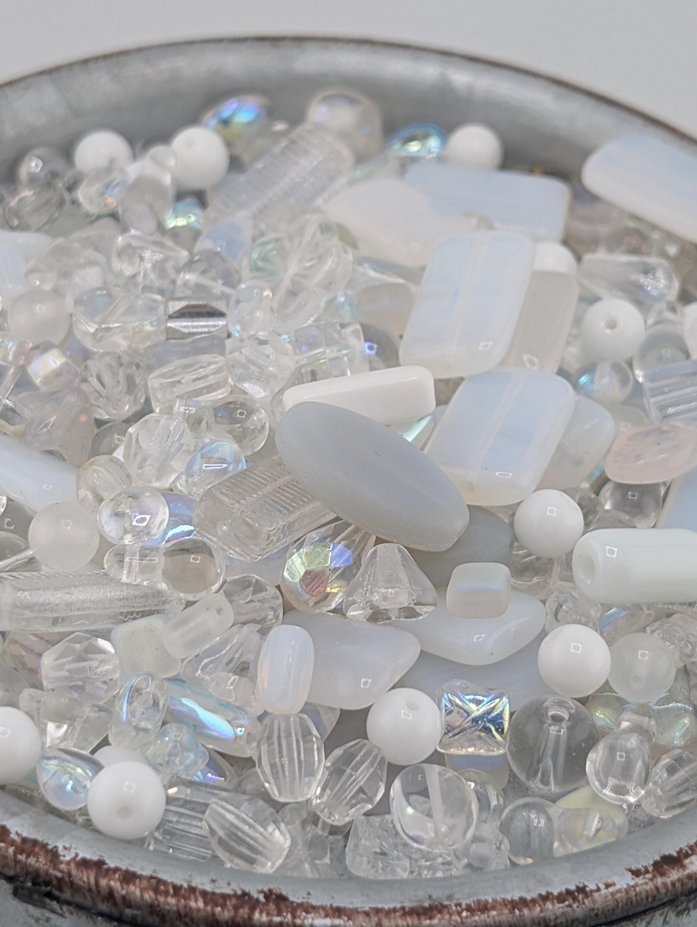 A bowl filled with various clear glass beads and crystals, including clear beads, clear crystals, and clear glass beads.