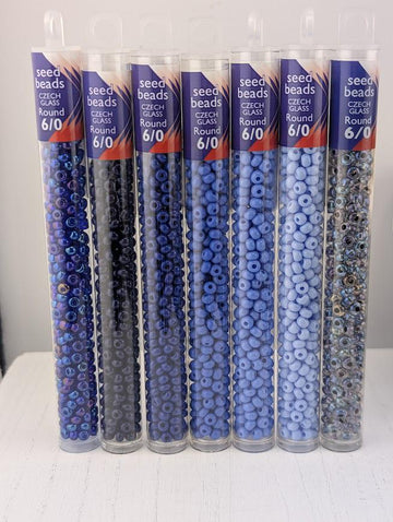 A collection of clear glass tubes filled with various shades of blue beads, arranged in a row.
