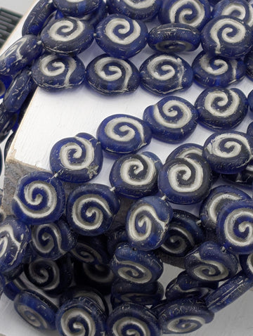 a collection of blue and white spiral beads arranged in a pattern, with some beads overlapping each other.
