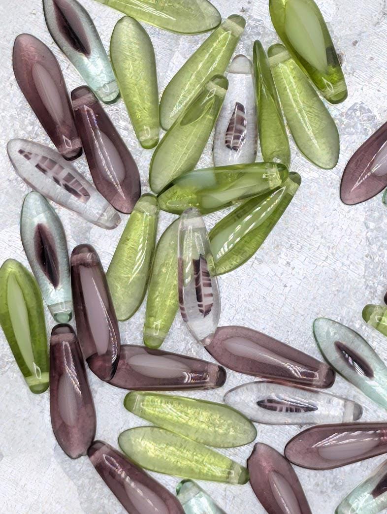 a collection of various colored glass beads, including green, purple, and clear beads, arranged in a visually appealing manner.