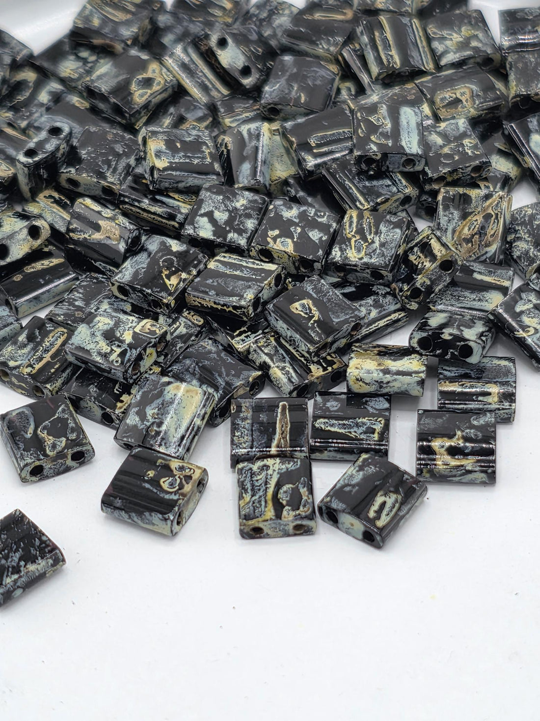 a collection of black and gold beads scattered on a white background.