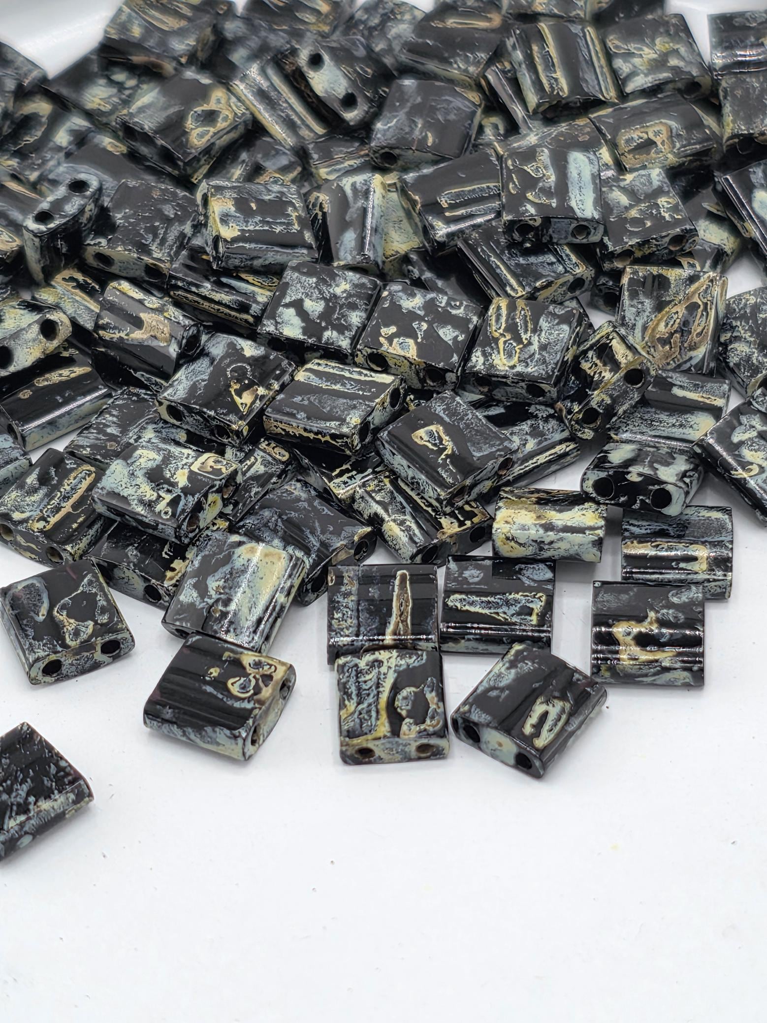 a collection of black and gold beads scattered on a white background.