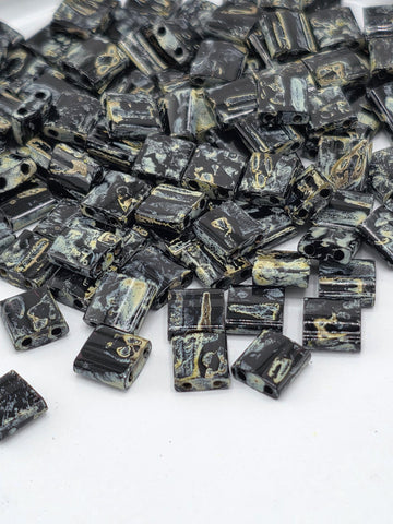 a collection of black and gold beads scattered on a white background.