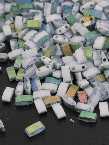 The image is a close-up of a pile of small, colorful beads or objects scattered on a dark surface.