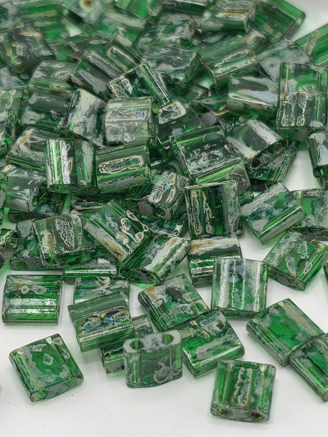 a collection of green glass beads or stones scattered on a white surface.