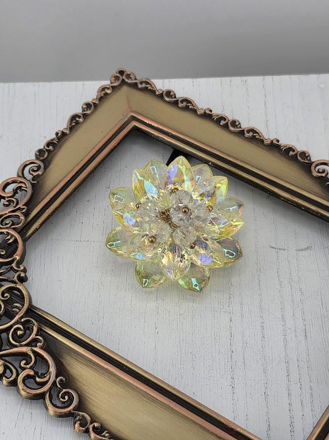 A decorative crystal flower-shaped object is displayed in a white ornate frame against a black background.
