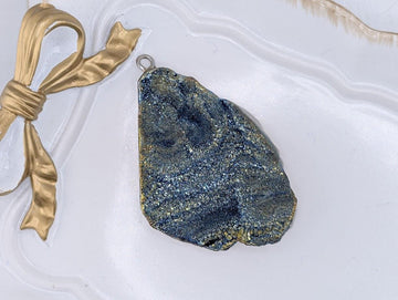 a large, irregularly shaped rock with a blue and gold color pattern, resting on a white surface.