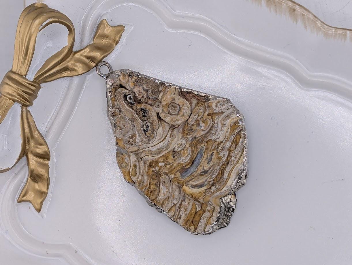 a large, irregularly shaped rock with a unique, striped pattern, possibly resembling a piece of amber or amberite. The rock is displayed on a white surface, with a gold ribbon or bow tied around it, creating a decorative and elegant presentation.
