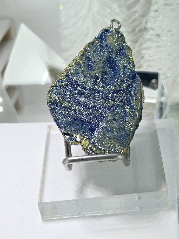 a piece of blue and green crystal or gemstone, possibly a piece of jade or a similar type of mineral, displayed on a clear stand.