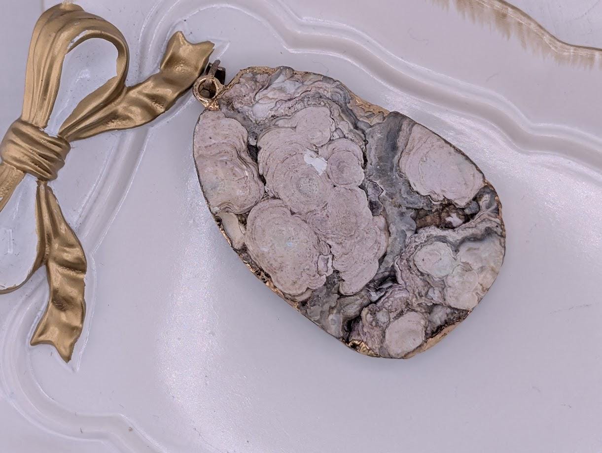 a large, irregularly shaped rock with a unique, natural pattern. The rock is placed on a white surface, and there is a gold ribbon or bow next to it.