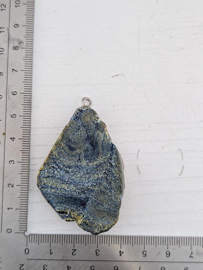 a close-up of a piece of blue and gold rock or gemstone, with a ruler placed next to it to provide a scale reference.