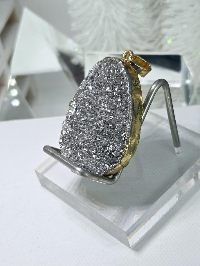 A large, irregularly shaped piece of gray rock with a gold-colored accent, displayed on a clear stand.