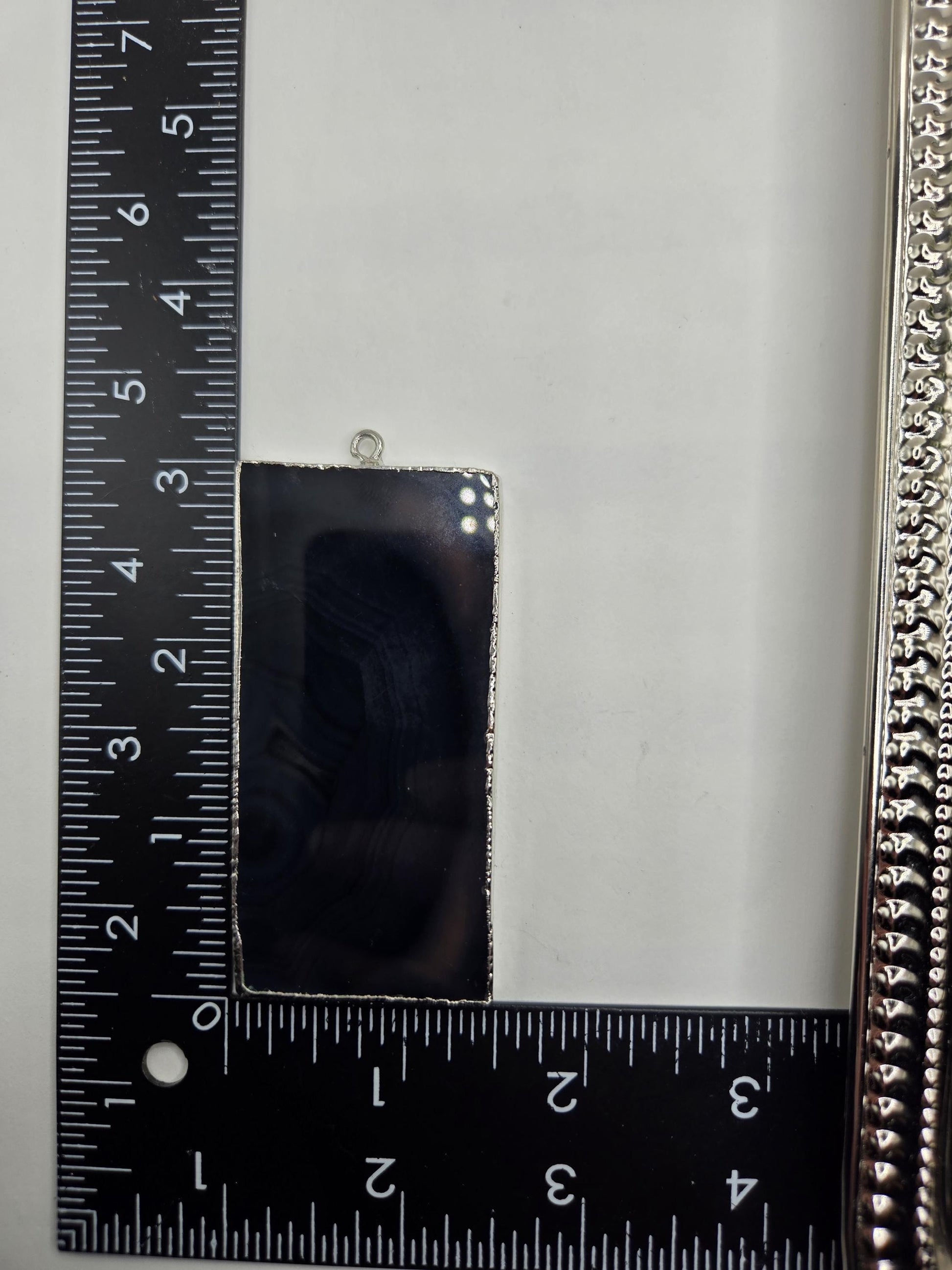 a close-up view of a ruler and a rectangular object, with the ruler providing a scale reference for the object's size.
