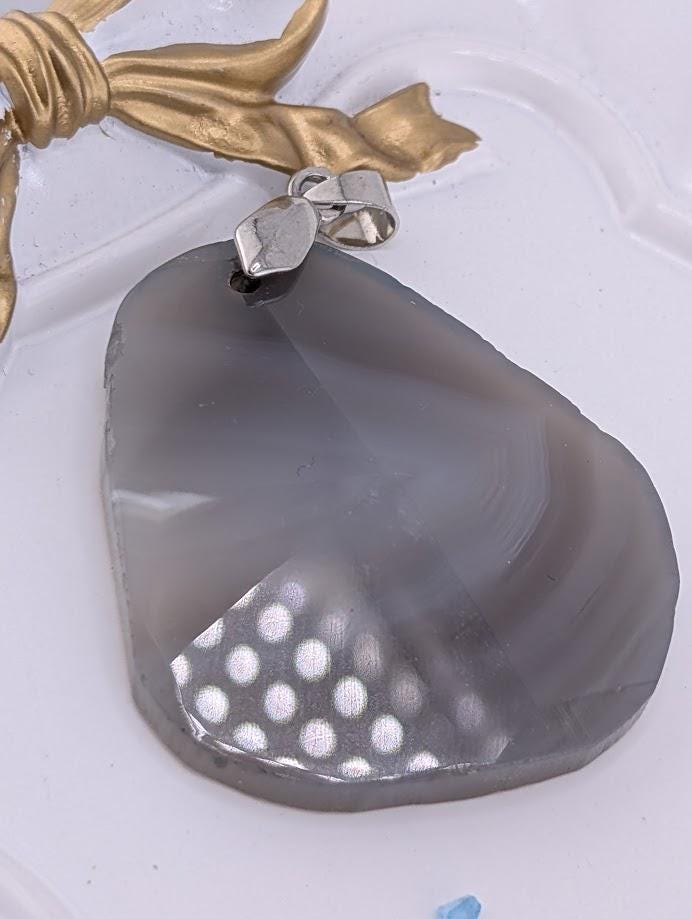 a close-up view of a grey stone with a polka dot pattern, resting on a white surface.