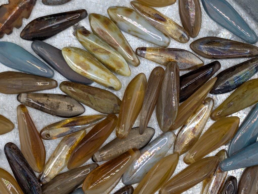 a collection of various colored glass beads, including shades of brown, yellow, and blue, arranged in a visually appealing manner.