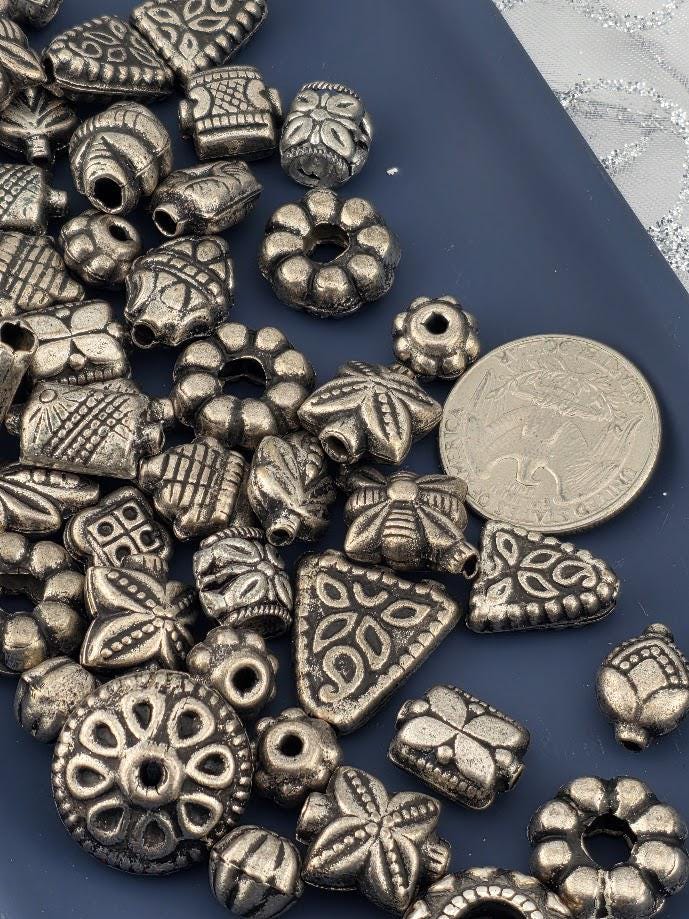 a collection of various metal beads and coins scattered on a blue surface.