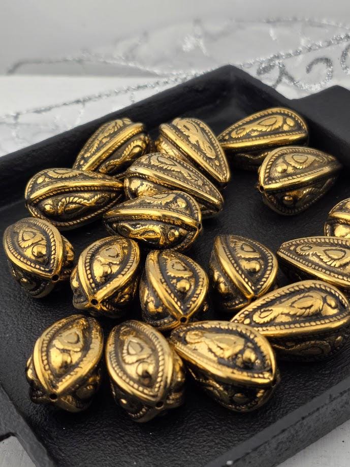 a collection of ornate, golden-colored metal beads arranged on a black surface.