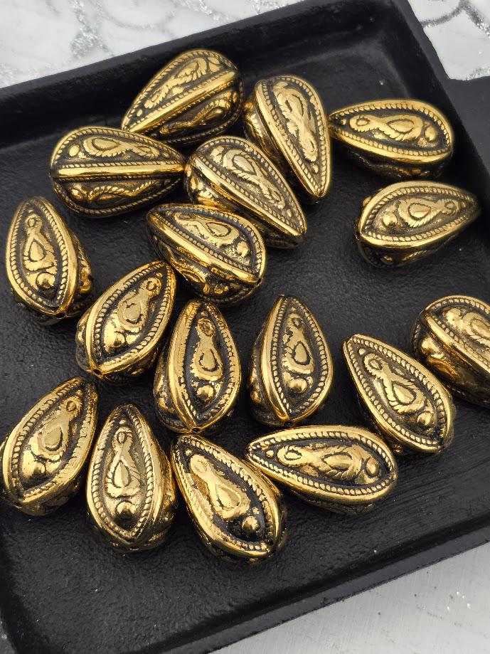 a collection of ornate, golden-colored metal beads arranged on a black surface.