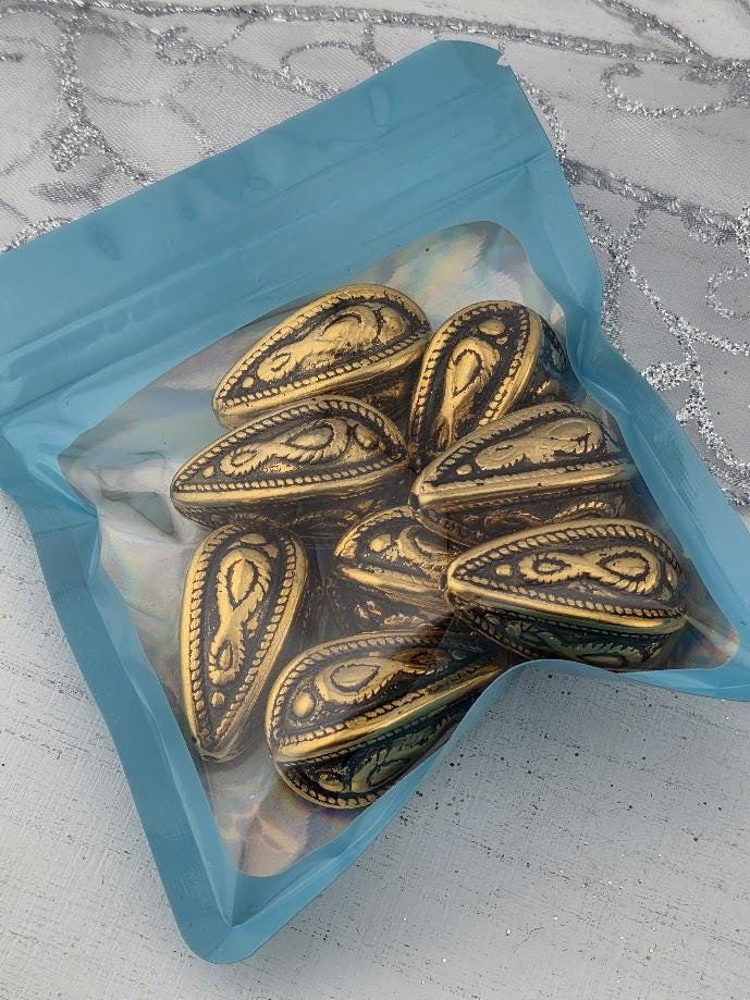 A blue plastic bag filled with decorative golden objects, such as beads or pendants, is shown in the image.