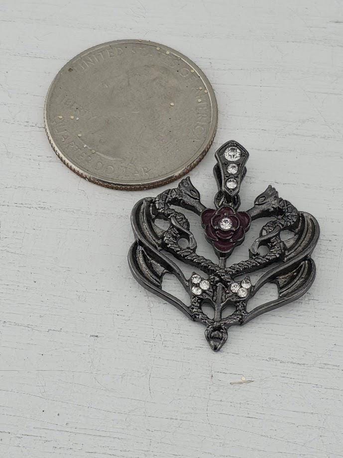 A decorative brooch with a floral design and sparkling gemstones is displayed in a white box, accompanied by a gift box with a red ribbon.