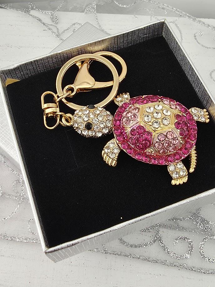 A keychain with a pink and gold turtle design, featuring rhinestones and a gold-colored charm.