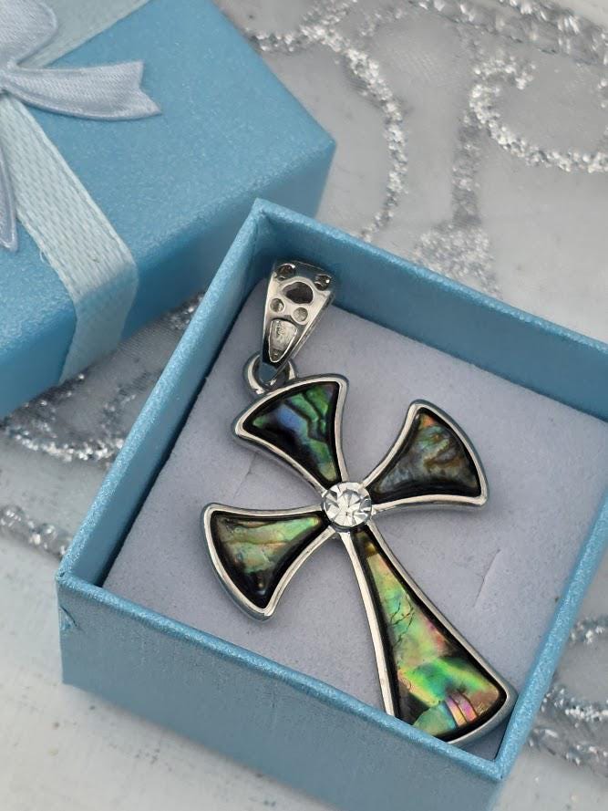 A silver cross pendant with colorful inlays is displayed in a blue gift box, with a silver clasp and a white ribbon bow.