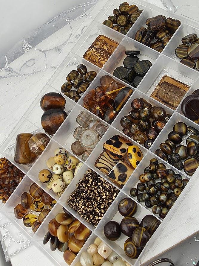 A clear plastic container filled with various beads and trinkets, including glass beads, wooden beads, and other decorative items.