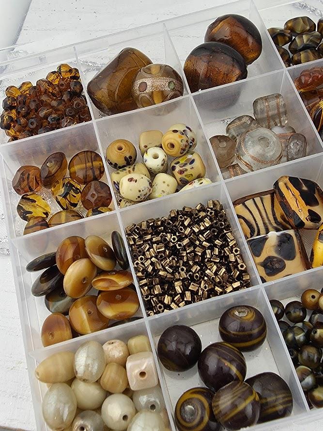 A clear plastic container filled with various beads and beads in different shapes and sizes, including some that appear to be made of glass.