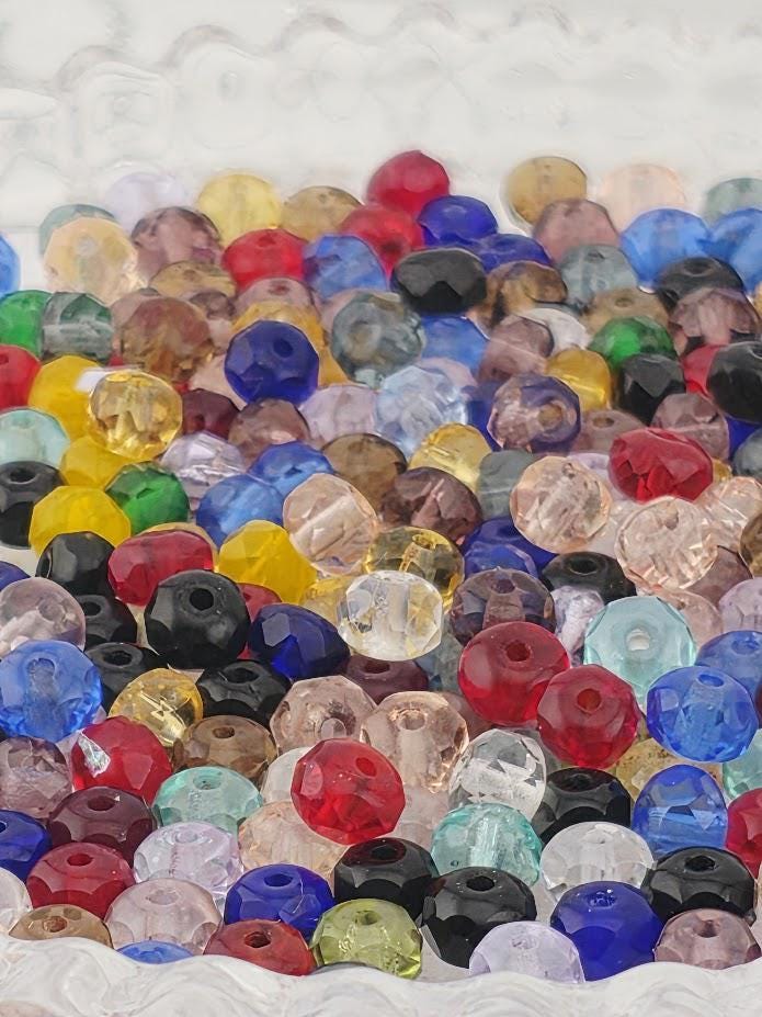 The image is a vibrant display of various colored glass beads, including red, blue, green, yellow, and purple, arranged in a visually appealing manner.