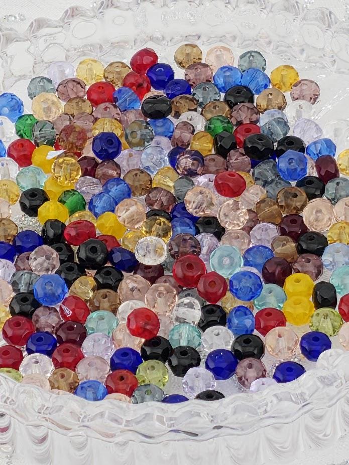 A colorful assortment of glass beads in various shapes, sizes, and colors, including red, blue, green, yellow, and purple, arranged in a visually appealing manner.