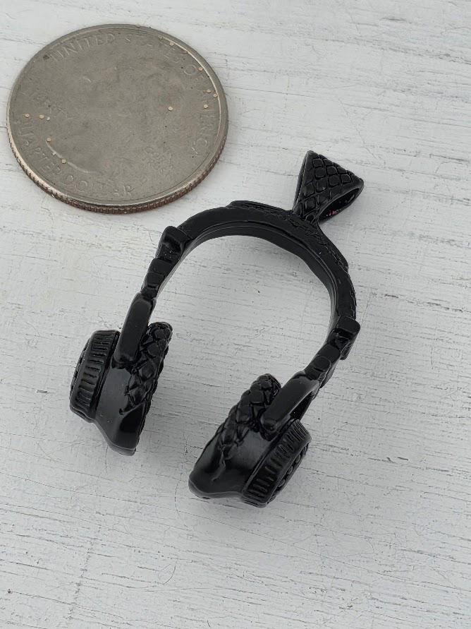 A pair of black headphones is displayed in a white box, with a gold gift box and a red ribbon visible in the background.